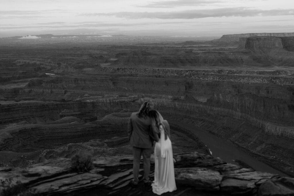 Couple looking out over the canyon at Dead Horse State Park before sunrise near Moab