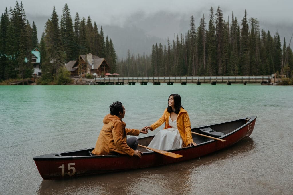 Couple on a canoe during their elopement while it's sprinkling rain